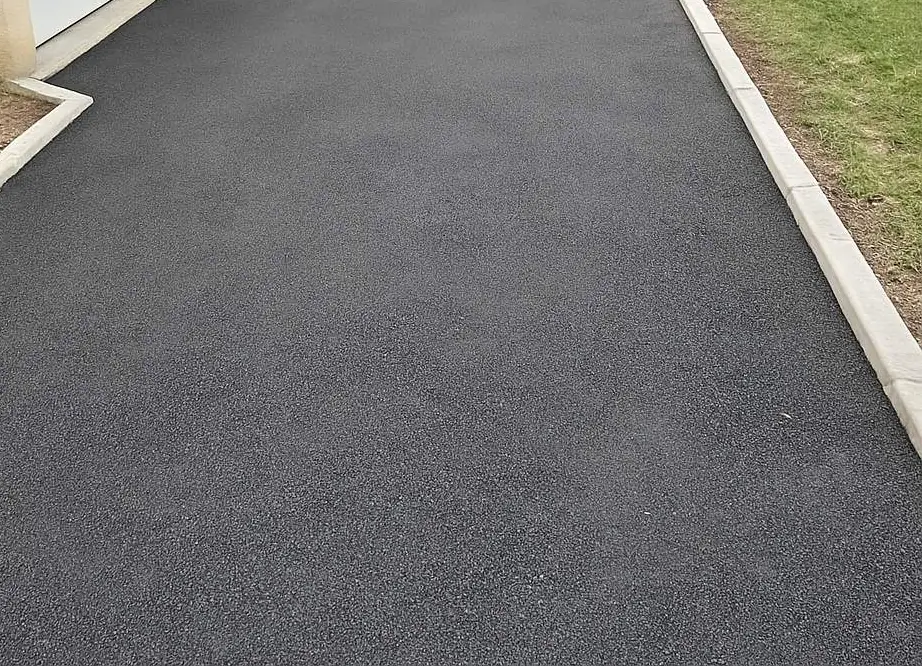 Enrobé noir neuf le long d'une bordure béton et d'une pelouse